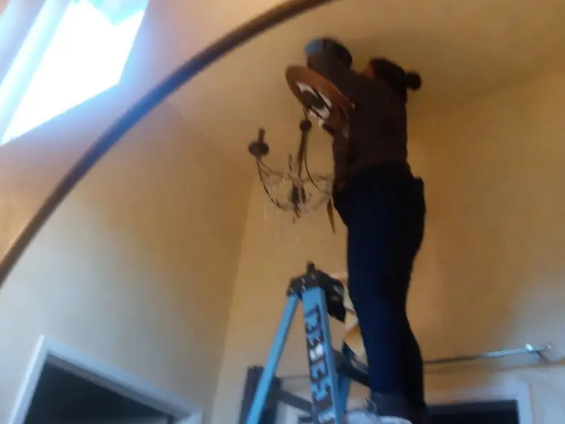 Electrician installing a chandelier in a Nixa residence